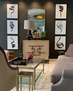 Art work by Elyse Defoor mounted on black frames on a dark gray wall in a living room setting.